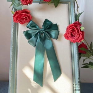 Dunkelgrüne Satin-Haarschleife mit langen Bändern in einem Vintage-Blumenrahmen