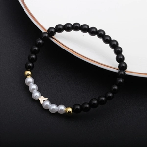 Detail of 6mm black agate beads and faux pearls on a bracelet with butterfly charm