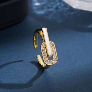 Luxury gold enamel ring with white inlay and pavé diamonds on a dark textured background