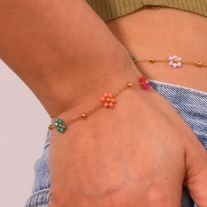 Detail of a gold plated link chain necklace with seven colorful resin flower charms