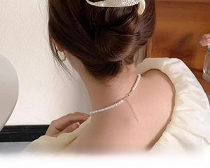 Close-up of elegant pearl necklace and sparkling gold crystal hair clip on female model
