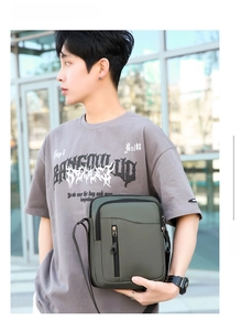 Borsa a tracolla da uomo in tessuto oxford verde oliva indossata da un modello in città