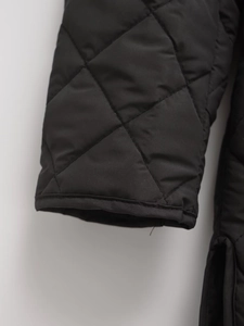 Detailed view of the diamond quilted pattern and stitching on a black jacket sleeve