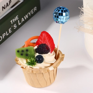 Macro shot of disco mirror ball cake topper on a fruit-topped cupcake with berries
