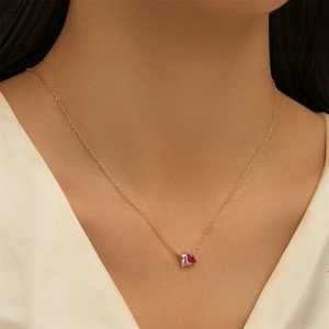 Detailed view of a gold necklace featuring pink rectangular and burgundy teardrop stones