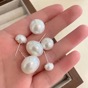 Minimalist round pearl stud earrings set with high luster white pearls and silver posts