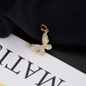 Macro shot of gold butterfly pendant with sparkling cubic zirconia on MATI branded paper