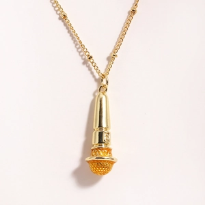 Macro shot of gold microphone pendant showing detailed mesh texture on stainless necklace