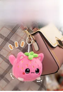 Cute strawberry cat plush keychain with pink soft fur and green leaf detail on a bag