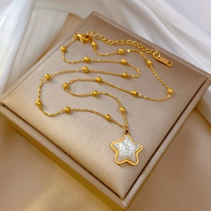 Star pendant necklace with shell inlay and gold beads on a champagne gift box