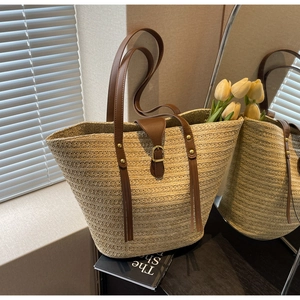 Close-up of woven straw tote bag with brown leather straps and artistic lighting