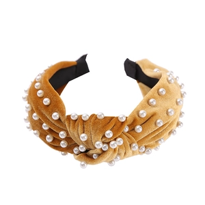 Detail of knotted velvet headband in golden yellow with white pearl beads decoration
