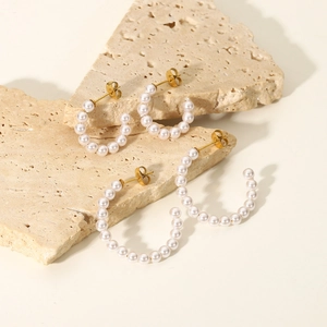 Detailed view of 18K gold plated stainless steel C-shaped earrings with white pearls