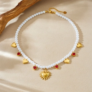 Gold-plated pearl necklace with sunburst heart pendant and red gemstone accents