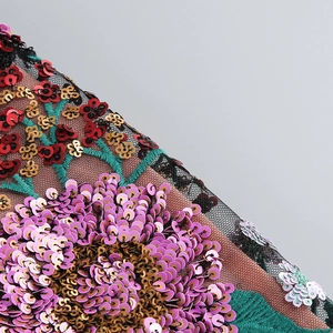 Gros plan sur une broderie de paillettes florales de luxe violettes et dorées sur tulle