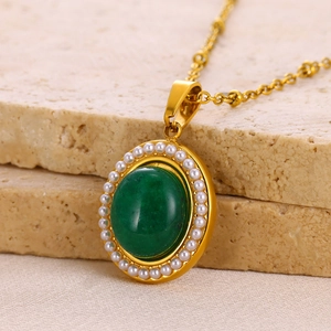Detail of vintage emerald pendant necklace with white pearl border on gold-plated chain