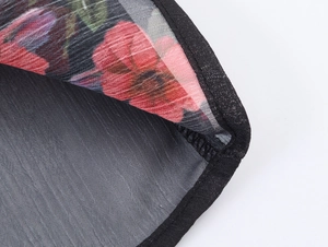 Dettaglio del tessuto in chiffon trasparente floreale con cuciture nere sull'orlo