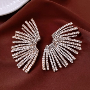 Vue détaillée de boucles d'oreilles dorées en éventail avec strass sur de la soie