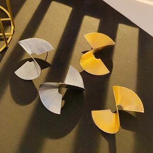 Gros plan de boucles d'oreilles abstraites en éventail avec plis dorés et argentés