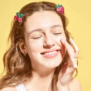 Model wearing strawberry and cherry fruit hair clips against a bright yellow background