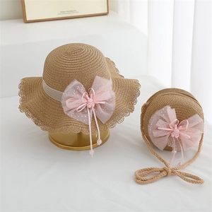 Detail of children's straw hat and matching bag with pink bows and lace trim