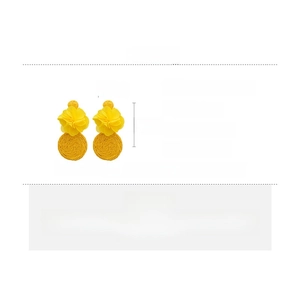 Detailed view of yellow fabric flower earrings with woven straw pendants and silver needles