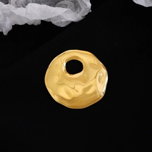 Detailed view of irregular golden circular brooch with hammered metal texture on black