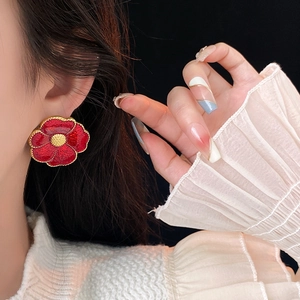 Detail of vintage red enamel flower earrings with gold plating worn by a female model