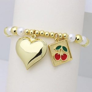 Fashionable gold beaded bracelet with pearl accents, heart charm and cherry pendant