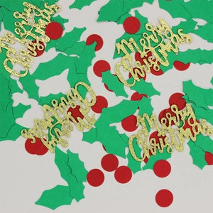 Detail of glitter Merry Christmas lettering with green holly leaves and red dot confetti