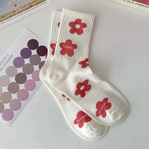 Dettaglio di calze in cotone bianco con motivi a fiori rossi e scritta FLOWER