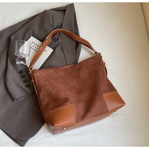Detailed view of brown suede tote bag with contrast stitching and leather patch accents