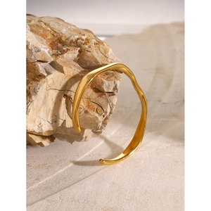 Polished 18k gold stainless steel open bangle with minimalist wavy design on natural stone
