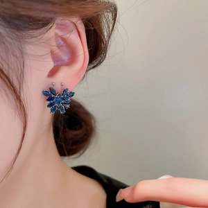 Primo piano di una modella che indossa piccoli orecchini a farfalla in zircone blu