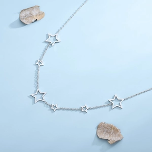 Minimalist silver star necklace with hollow star pendants on light blue background