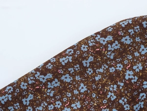 Close-up of floral chiffon fabric with blue and pink patterns on a dark brown base