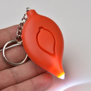 Close-up of orange leaf-shaped personal alarm keychain with glowing white LED light