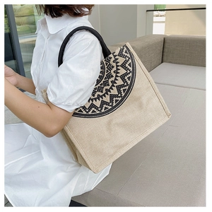 Detailed texture of ethnic linen tote bag featuring black geometric patterns and woven handle