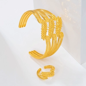 Detail of gold hollow leaf bangle and ring set with intricate carved texture
