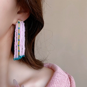 Gros plan de boucles d'oreilles à pompons roses perlées portées par un mannequin