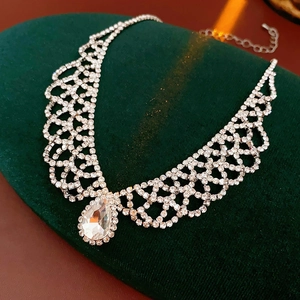 Close-up of silver rhinestone necklace with teardrop pendant on green velvet display