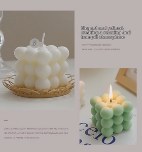 Detail of bubble scented candles in white and green on woven coaster and art book