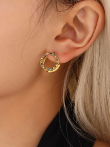 Primer plano de pendientes de aro dorados con cristales pavé multicolores en una modelo