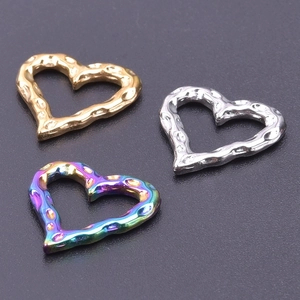 Macro shot of three heart-shaped pendants in gold, silver, and rainbow hammered finish