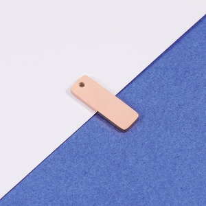Vue macro d'un pendentif rectangulaire en acier inoxydable or rose avec trou de suspension