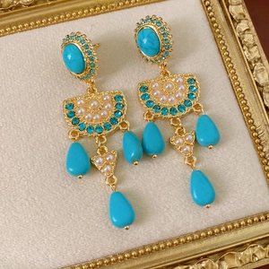 Detailansicht von Vintage-Goldohrringen mit türkisfarbenen Steinen und blauen Zirkonen