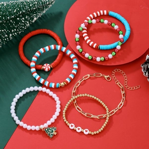 Détail du lot de bracelets de Noël avec perles d'argile et breloques sur décor de sapin