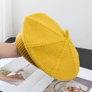 Detail of a bright yellow knitted wool beret showing its warm woven texture and 3D shape