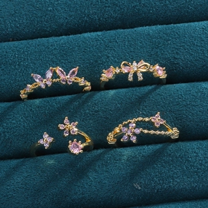 Détail macro de quatre bagues dorées avec motifs papillon et fleurs sur velours violet