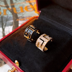 Macro view of C-shaped earrings with Greek key patterns in black enamel and crystal pave